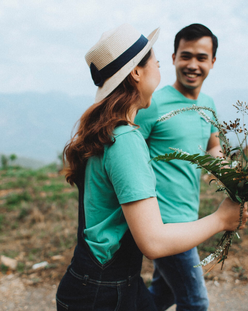 People walking wearing matching t-shirts smiling while holding a bouquet of wild flowers